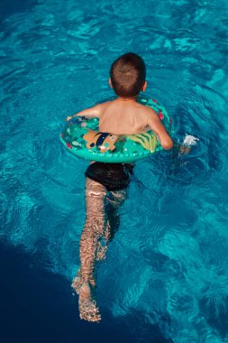 Bir çocuk can simidiyle havuzda tek başına yüzer. Temiz su. Yukarıdan bak. Yüksek kalite fotoğraf