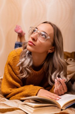 Kanepede kitabı olan bir kadın. Bir kadın kitap okuyor. Evde öğreniyorum. Yüksek kalite fotoğraf