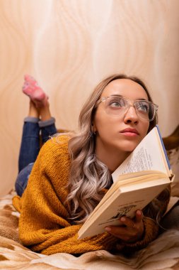 Kanepede kitabı olan bir kadın. Bir kadın kitap okuyor. Evde öğreniyorum. Yüksek kalite fotoğraf