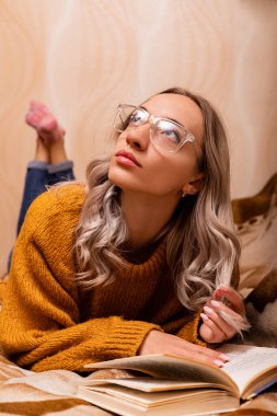 Bir öğretmen evde kanepede bir kitap okur. Dünya Bilgi Günü. Yüksek kalite fotoğraf