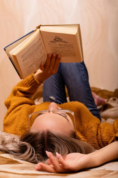 A teacher reads a book at home on the couch. World Knowledge Day. High quality photo