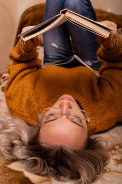 Evdeki kanepede kitap okuyan bir kadın. Merkez ofis. Uzaktan Öğrenme. Yüksek kalite fotoğraf
