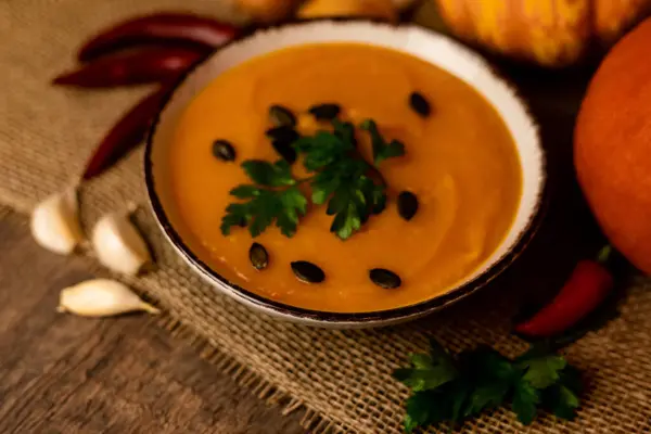 A bowl of pumpkin soup with vegetables on the table. Rustic autumn food. Diet soup. High quality photo