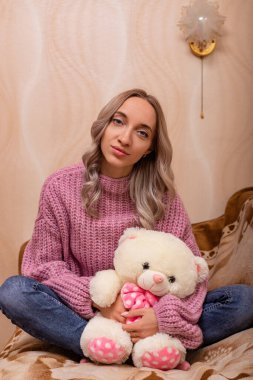 Kanepede oyuncak ayıyla oturan kadın. Pelüş oyuncakla geçmişe dönük fotoğraf. Yüksek kalite fotoğraf