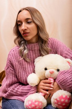 Kanepede oyuncak ayıyla oturan kadın. Pelüş oyuncakla geçmişe dönük fotoğraf. Yüksek kalite fotoğraf