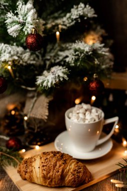 Bir fincanda şekerleme ve Noel ağacının yanındaki masada kruvasan standı. Yılbaşı gecesi evde. Yüksek kalite fotoğraf
