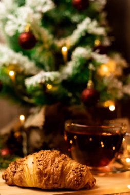 Noel ağacının yanında bir fincan kruvasanla çay. Yılbaşı gecesi evde ailemle olacağım. Yüksek kalite fotoğraf