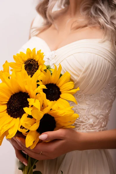 Bride in a wedding dress with a bouquet of sunflowers. Beautiful woman. Floristics. High quality photo