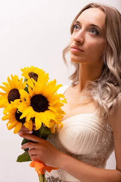 Bride in a wedding dress with a bouquet of sunflowers. Beautiful woman. Floristics. High quality photo