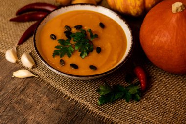 A bowl of pumpkin soup on the table. Autumn vegetables. Homemade food. Healthy nutrition. High quality photo clipart