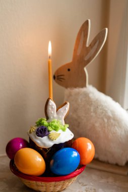 Yanmış mumlu Paskalya pastası. Masadaki sepetteki Paskalya renkli yumurtalar. Yüksek kalite fotoğraf