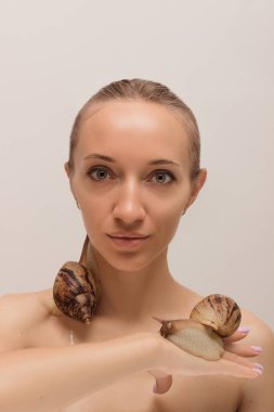 Yüzünde salyangozlar olan güzel genç bir kadın. Yenilenme prosedürleri. Yüksek kalite fotoğraf