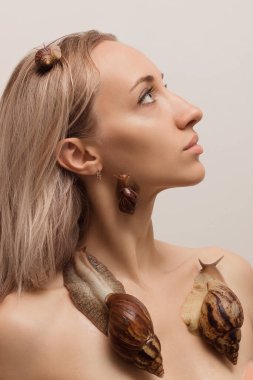 Yüzünde salyangozlar olan güzel genç bir kadın. Yenilenme prosedürleri. Yüksek kalite fotoğraf