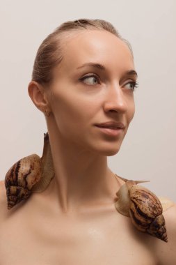 Yüzünde salyangozlar olan güzel genç bir kadın. Yenilenme prosedürleri. Yüksek kalite fotoğraf