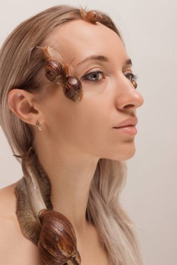 Yüzünde salyangozlar olan güzel genç bir kadın. Yenilenme prosedürleri. Yüksek kalite fotoğraf