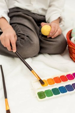 Paskalya Tavşanı Kulaklı Küçük Çocuk, Beyaz Arkaplanda Paskalya Yumurtası Boyuyor. Yüksek kalite fotoğraf