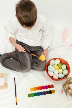 Paskalya Tavşanı Kulaklı Küçük Çocuk, Beyaz Arkaplanda Paskalya Yumurtası Boyuyor. Yüksek kalite fotoğraf
