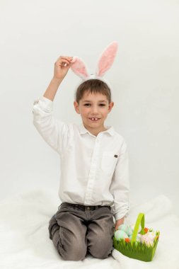 Paskalya Tavşanı Kulaklı Küçük Çocuk, Beyaz Arkaplanda Paskalya Yumurtası Boyuyor. Yüksek kalite fotoğraf