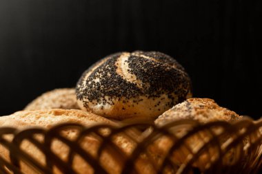 Haşhaş tohumlu taze pişmiş çörek. Çeşitli taze hamur işleri. Masanın üzerinde hasır bir sepetin içinde ekmek. Yüksek kalite fotoğraf