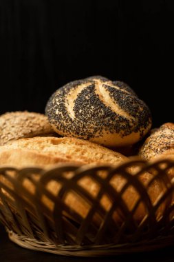Haşhaş tohumlu taze pişmiş çörek. Çeşitli taze hamur işleri. Masanın üzerinde hasır bir sepetin içinde ekmek. Yüksek kalite fotoğraf