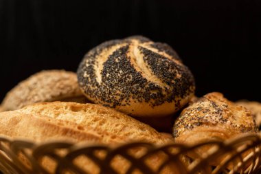 Haşhaş tohumlu taze pişmiş çörek. Çeşitli taze hamur işleri. Masanın üzerinde hasır bir sepetin içinde ekmek. Yüksek kalite fotoğraf