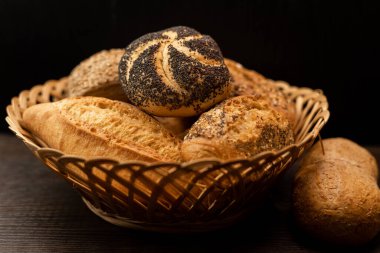 Haşhaş tohumlu taze pişmiş çörek. Çeşitli taze hamur işleri. Masanın üzerinde hasır bir sepetin içinde ekmek. Yüksek kalite fotoğraf