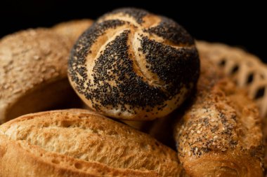 Haşhaş tohumlu taze pişmiş çörek. Çeşitli taze hamur işleri. Masanın üzerinde hasır bir sepetin içinde ekmek. Yüksek kalite fotoğraf