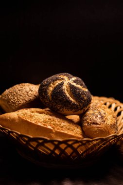 Haşhaş tohumlu taze pişmiş çörek. Çeşitli taze hamur işleri. Masanın üzerinde hasır bir sepetin içinde ekmek. Yüksek kalite fotoğraf