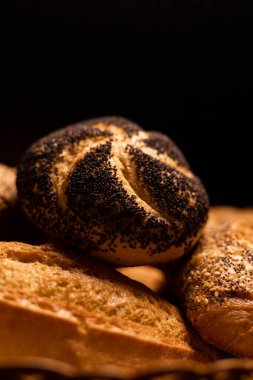 Haşhaş tohumlu taze pişmiş çörek. Çeşitli taze hamur işleri. Masanın üzerinde hasır bir sepetin içinde ekmek. Yüksek kalite fotoğraf