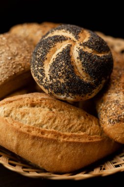 Haşhaş tohumlu taze pişmiş çörek. Çeşitli taze hamur işleri. Masanın üzerinde hasır bir sepetin içinde ekmek. Yüksek kalite fotoğraf