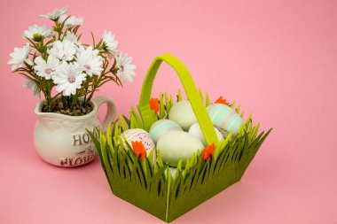 Pembe arka planda yeşil sepetli Paskalya yumurtaları. Paskalya. Paskalya Kompozisyonu. Yüksek kalite fotoğraf