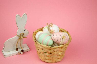 Pembe arka planda hasır sepette paskalya yumurtaları. Paskalya yumurtaları ve bir tavşan. Yüksek kalite fotoğraf