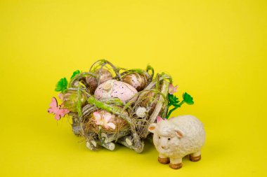 Sarı arka planda Paskalya yumurtası ve koyun. Paskalya yumurtalarının yanında bir koyun heykeli. Yüksek kalite fotoğraf