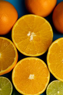 Mavi arkaplandaki portakalları yakın plan kes. C vitamini.