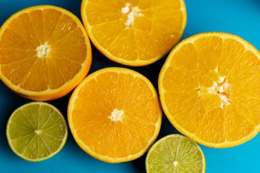 Mavi arkaplandaki portakalları yakın plan kes. C vitamini.