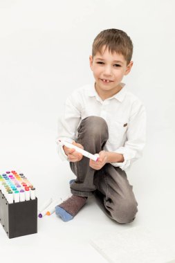 Öğrenci kalemlerle resim çizer. Beyaz arka planda bir çocuk. Çocuk keçeli kalemlerle dekore ediyor. Yüksek kalite fotoğraf