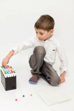 Öğrenci kalemlerle resim çizer. Beyaz arka planda bir çocuk. Çocuk keçeli kalemlerle dekore ediyor. Yüksek kalite fotoğraf