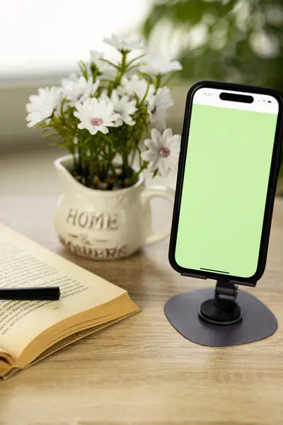Yeşil ekranlı bir cep telefonu. Akıllı telefon tezgahta. Büyüteçle kitap. Yüksek kalite fotoğraf