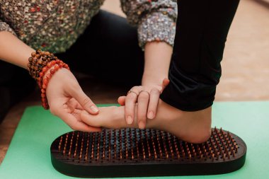 Terapist hastaların bacağını yoğurur. Bir kadın çivilerin üzerinde durmaya çalışıyor. Yüksek kalite fotoğraf