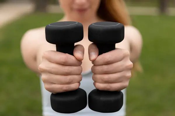 Dambılı, yüzü olmayan kadın elleri. Sokakta spor yapan bir kadın var. Dambılları elinize alın. Yüksek kalite fotoğraf