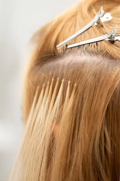 Saç uzatma işlemi. Saç stili değişikliği. Saç eklentileri olan bir sarışın. Yakın plan. Yüksek kalite fotoğraf