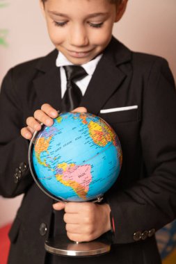 Gülümseyen mutlu okul çocuğu küreye bakıyor. Okulda coğrafya dersi. Yüksek kalite fotoğraf