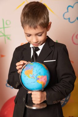 Coğrafya dersi. Bir öğrencinin elinde bir küre. Oğlan küreye bakıyor. Yüksek kalite fotoğraf