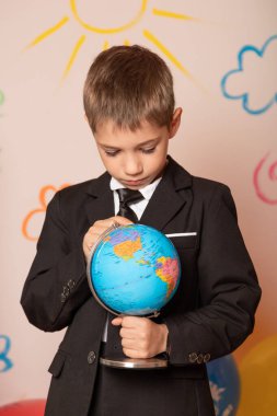 Bir okul çocuğu elinde bir küre tutuyor. Okulda coğrafya dersi. Dünyayı dolaşmak için. Yüksek kalite fotoğraf