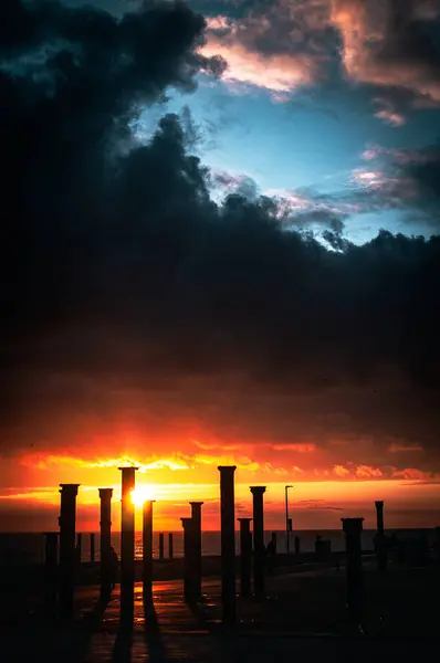 Günbatımı ve İskele, Brighton, Doğu Sussex, İngiltere 'de karanlık, ağır gökyüzü.