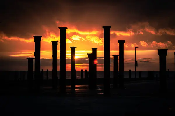 Günbatımı ve İskele, Brighton, Doğu Sussex, İngiltere 'de karanlık, ağır gökyüzü.