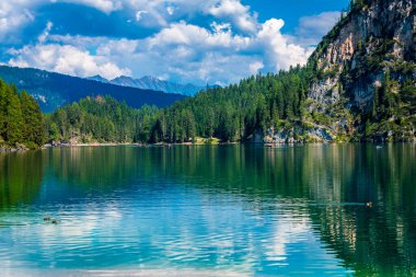 Dolomitler. Braies gölü ve tekneleri. Suda zümrüt renkleri.