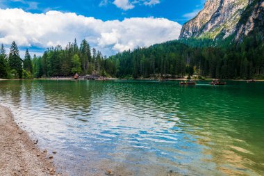 Dolomitler. Braies gölü ve tekneleri. Suda zümrüt renkleri.