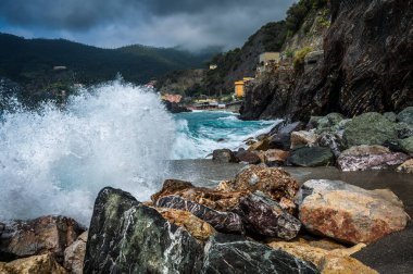 Dalgalar kayalık deniz kıyısına çarpıyor. Cinque Terre 'de. Monterosso, liman, sahil ve antik köy.                                  