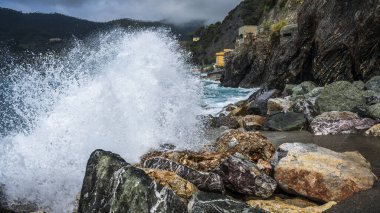 Dalgalar kayalık deniz kıyısına çarpıyor. Cinque Terre 'de. Monterosso, liman, sahil ve antik köy.                                  